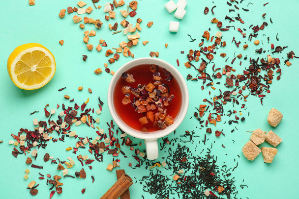 Composition avec tasse et tas de thé aux fruits secs sur fond turquoise - Photo, image