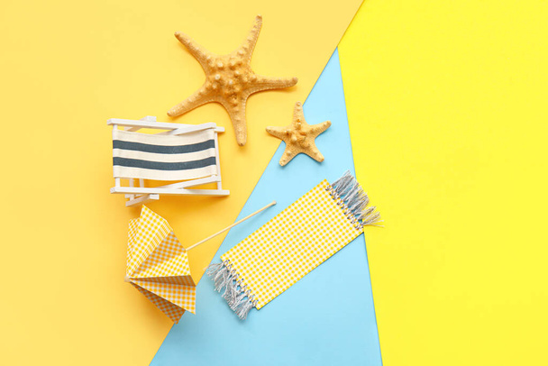 Composition with miniature deck chair, starfishes and paper umbrella on colorful background - Photo, Image