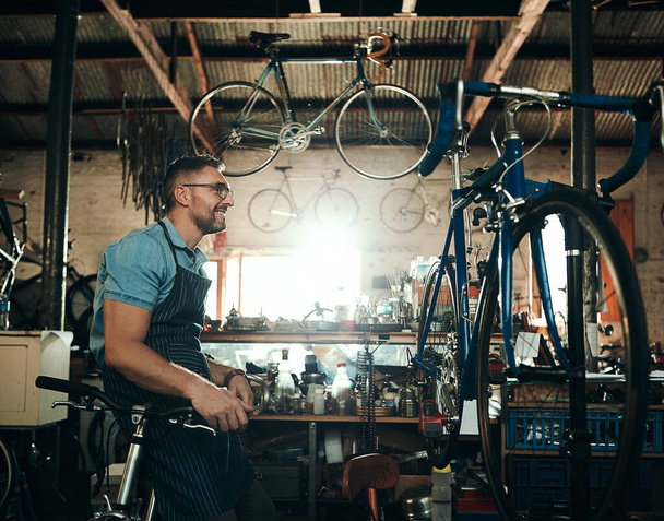 Tiene grandes planes para tu bicicleta. un hombre maduro que trabaja en un taller de reparación de bicicletas - Foto, imagen