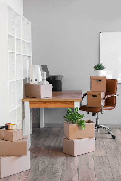 Workplace with cardboard boxes in office on moving day - Fotó, kép