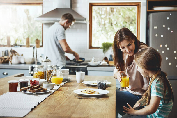 How about some juice. a family having breakfast together at home - Photo, Image