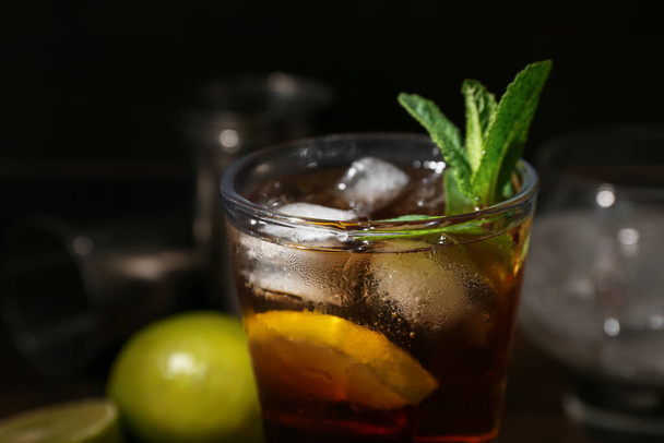 Glass of tasty Cuba Libre cocktail on dark background, closeup - Photo, image