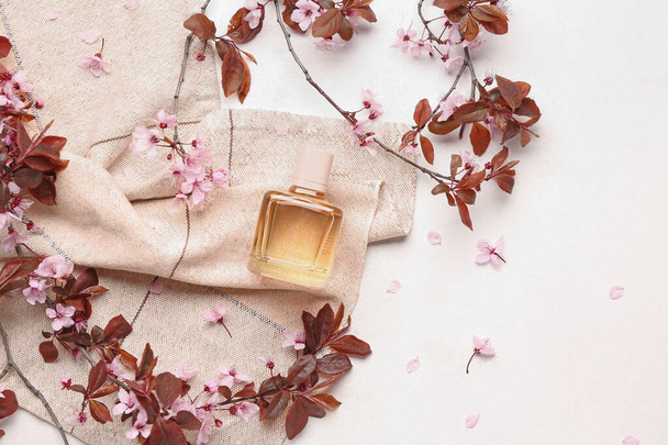 Hermosas ramas en flor y botella de perfume sobre fondo claro - Foto, imagen