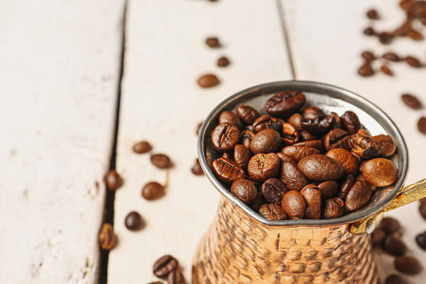 Pot with coffee beans on light wooden background - Zdjęcie, obraz