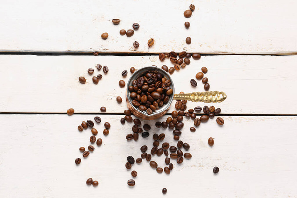 Pot with coffee beans on light wooden background - Photo, Image