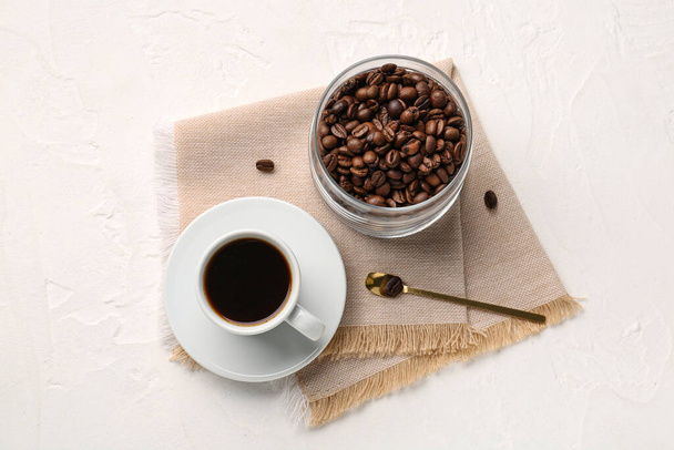 Tasse Kaffee und Glas mit Bohnen auf hellem Hintergrund - Foto, Bild