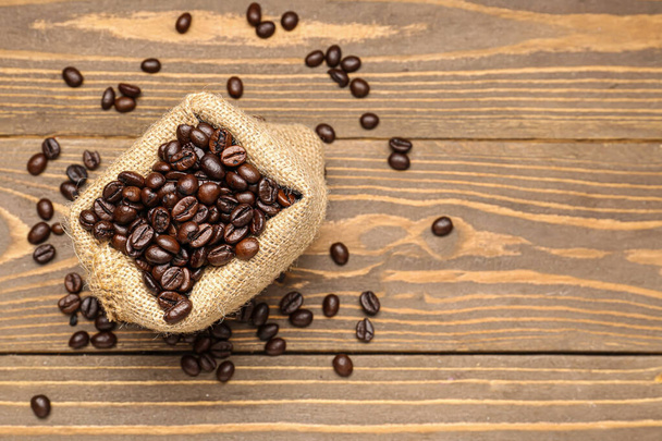 Мешок с кофейными зернами на деревянном фоне - Фото, изображение