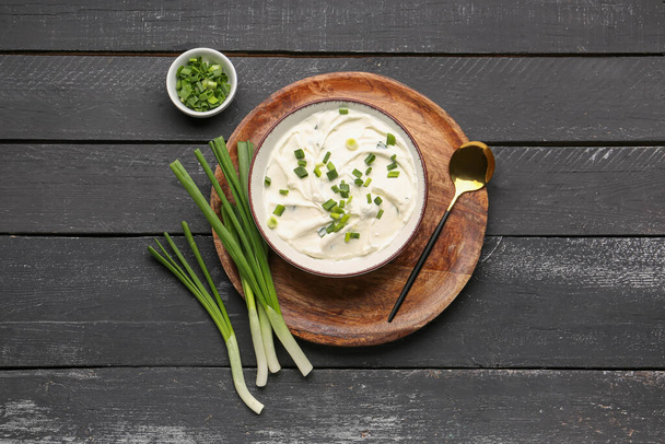 Bowl of tasty sour cream with green onion on dark wooden background - Photo, Image