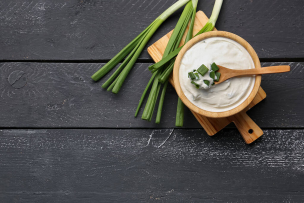 Bowl of tasty sour cream with green onion on dark wooden background - Foto, immagini