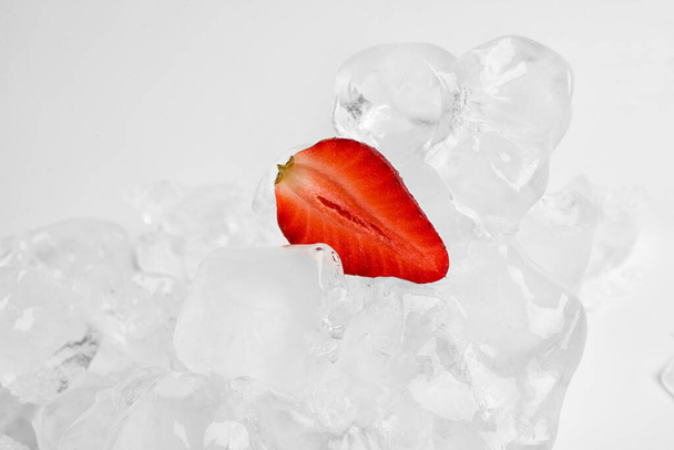 Нарезка свежей клубники и льда изолированы на белом фоне - Фото, изображение