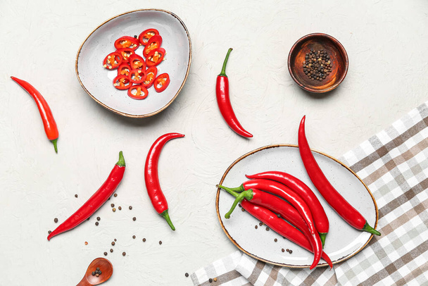 Plate and bowl with fresh chili peppers on light background - Photo, Image
