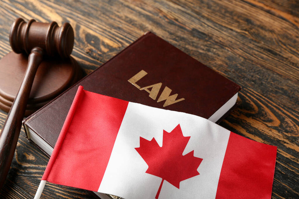 Flaga Kanady z książką prawniczą i młotkiem sędziowskim na drewnianym tle, zbliżenie - Zdjęcie, obraz