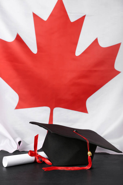 Graduation hat with diploma on table against flag of Canada - Photo, Image