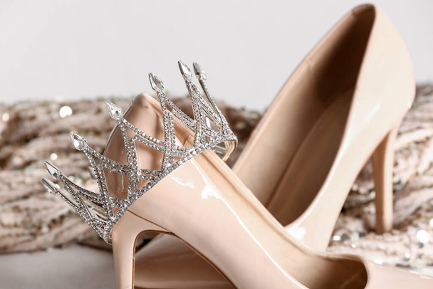 Beautiful crown with heels and prom dress on white table, closeup - Фото, изображение