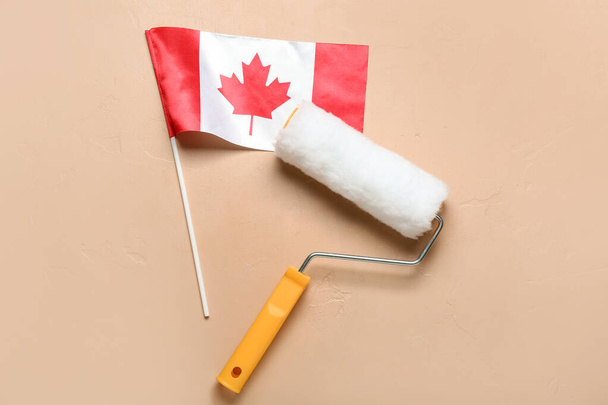 Flag of Canada with paint roller on beige background - Foto, afbeelding