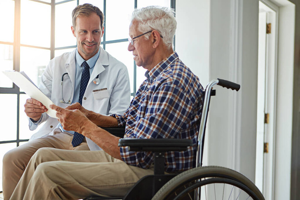 Well go through it together. a male doctor talking to a senior patient in the retirement home - Foto, imagen
