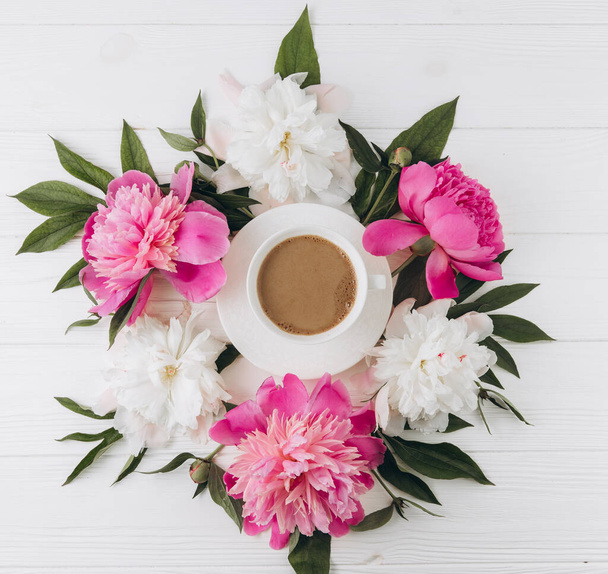Floral arrangement of pink and white peonies around a cup of coffee, flat lay, top view - 写真・画像
