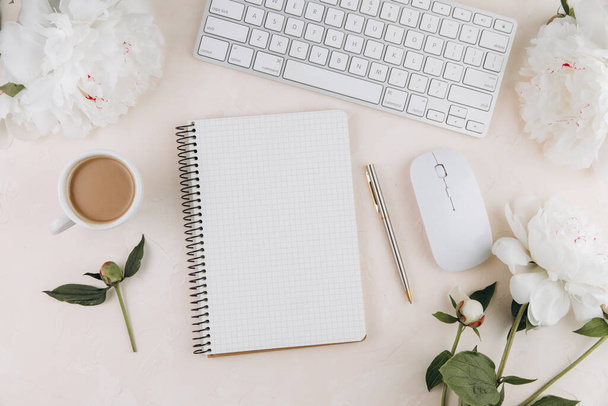 Espaço de trabalho feminino com bloco de notas aberto em branco e xícara de leite de café, teclado, material de escritório elegante e em um teble pastel - Foto, Imagem