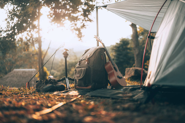 Camping equipment, bags, shoes, ukulele, tripod beside the tent in the morning. Object camp, Travel and vocation concept. - Fotografie, Obrázek
