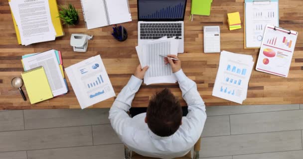 Empresário estudando mesa com números em papel e gráfico no laptop no escritório visão superior filme 4k. Estratégias de negócios para aumentar o conceito de lucros - Filmagem, Vídeo