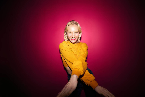 Eine fröhliche Frau tanzt und amüsiert sich isoliert auf magenta-farbenem Hintergrund. Viva magenta, Farbe des Jahres. - Foto, Bild