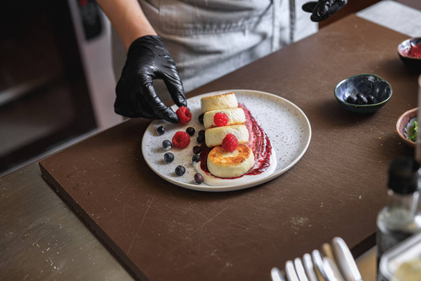 Chef decorado tartas de queso listo con bayas para el desayuno en la cocina del restaurante - Foto, Imagen