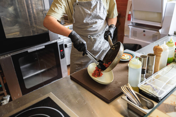 Chef zet kant en klare schotel van koekenpan in de plaat voor het serveren in restaurant - Foto, afbeelding