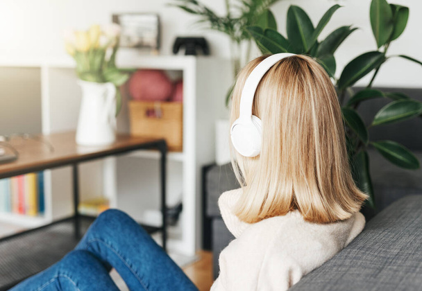 Mujer rubia joven en auriculares escuchando música y relajándose en casa. - Foto, Imagen