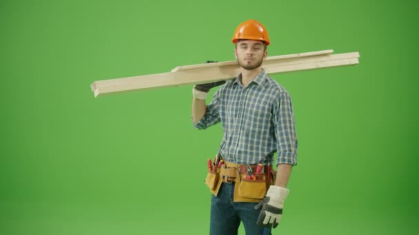 Mladý vousatý sebevědomý stavební inženýr v kostkované košili, tvrdém klobouku, pracovních rukavicích, koženém opasku, držení dřevěných prken na ramenou, vytváření OK gesta a při pohledu na úsměv fotoaparátu - Záběry, video