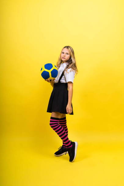 ポートレートのかわいいです8歳の女の子でバレーボール服絶縁上の赤黄色の背景 - 写真・画像