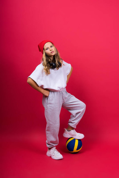 Portrait of cute eight year old girl in volleyball outfit isolated on a red yellow background - Foto, Imagem