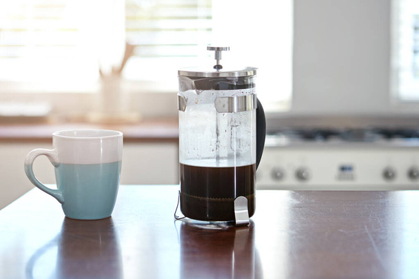 Commencez bien votre matinée. une tasse et une presse française sur un comptoir de cuisine - Photo, image