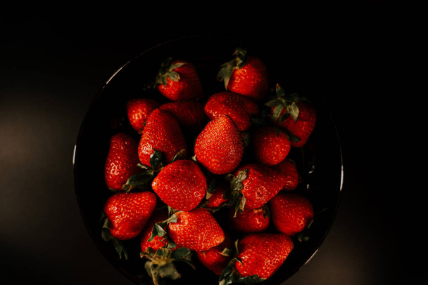 Fresas girando sobre un fondo negro. Fresa roja vibrante fresca y orgánica Snack vegano crudo de verano Close up - Foto, imagen