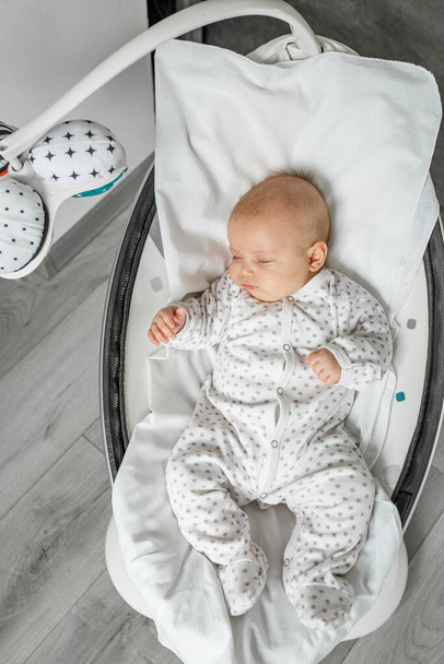 Adorable baby sleeps in baby swing in room. Newborn concept. - Zdjęcie, obraz