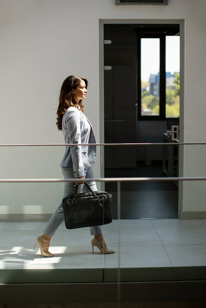 Pretty young business woman walking with briefcase in the office hallway - Fotografie, Obrázek