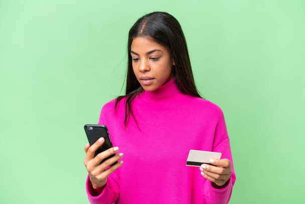 Молода афроамериканська жінка через ізольоване походження купує за допомогою мобільного телефону кредитною карткою - Фото, зображення