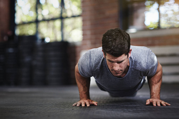 Your body achieves what you believe. a young man doing pushups in a gym - Photo, Image