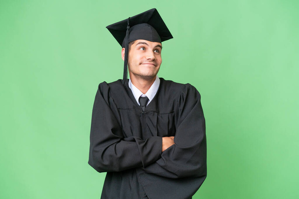 Mladý absolvent vysoké školy běloch přes izolované pozadí dělat pochybnosti gesto při zvedání ramen - Fotografie, Obrázek