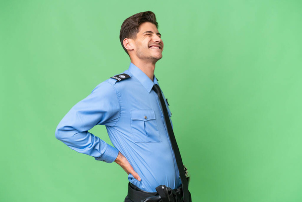 Junger Polizist mit isoliertem Hintergrund leidet unter Rückenschmerzen, weil er sich bemüht hat - Foto, Bild