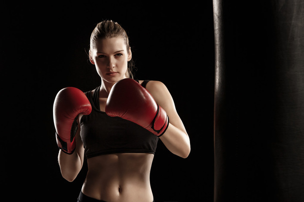 beautiful woman is boxing on black background - 写真・画像