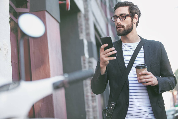 Posti dove stare, persone da vedere. un giovane elegante che usa un cellulare mentre cammina in città - Foto, immagini