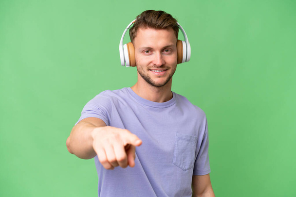 Young blonde caucasian man over isolated background listening music - Photo, Image