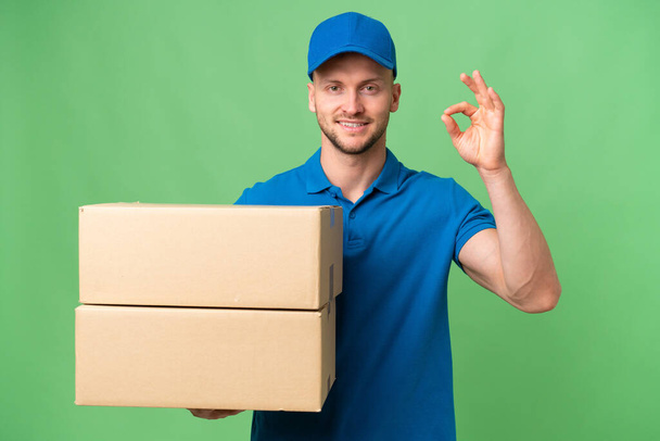 Delivery caucasian man over isolated background showing ok sign with fingers - Photo, Image