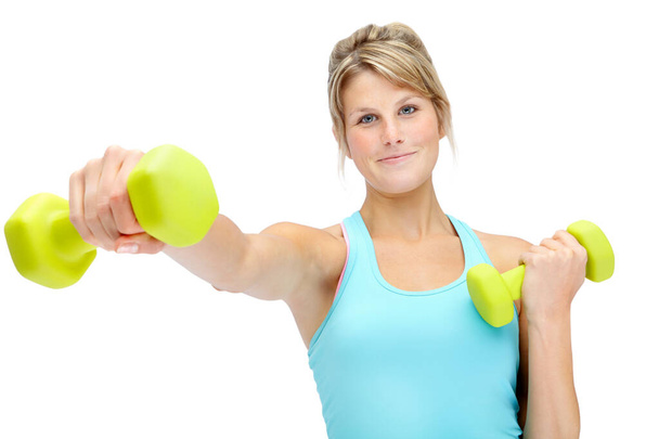 Getting shape for a healthier lifestyle. Sporty young woman lifting dumbbells while isolated on white - Foto, Bild
