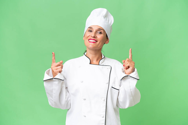 Kobieta w średnim wieku kucharz na odosobnionym tle wskazując na świetny pomysł - Zdjęcie, obraz