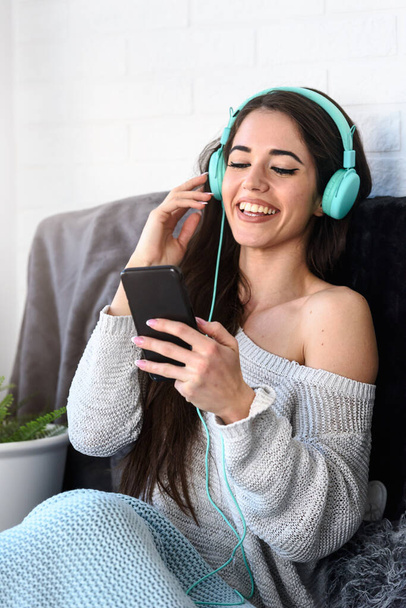 hermosa mujer joven escuchando música con auriculares en casa - Foto, imagen