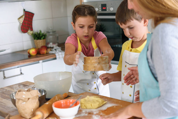 mother, daughter and son cooking pastry together, working with dough - Photo, image