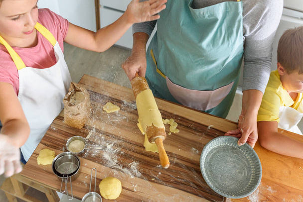 madre, hija e hijo cocinando pastelería juntos, trabajando con masa - Foto, imagen