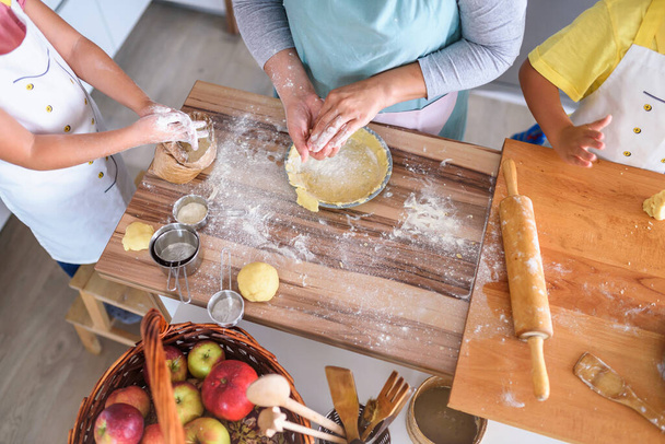 madre, figlia e figlio cucinano insieme la pasticceria, lavorando con la pasta - Foto, immagini