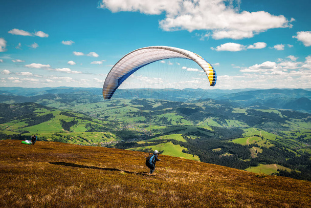 Gleitschirm startet zum Fliegen. Fallschirm füllt sich mit Luft in den Bergen an sonnigen Tagen. Thema Sport und Erholung - Foto, Bild
